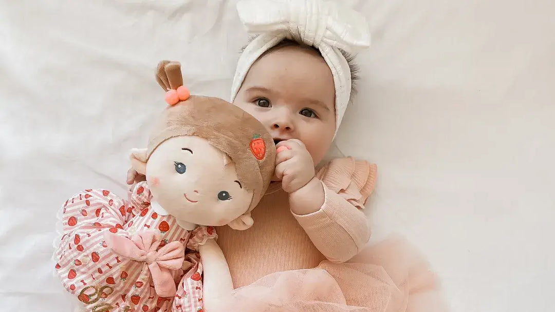 Baby girl chewing Strawberry Girl plush doll during playtime