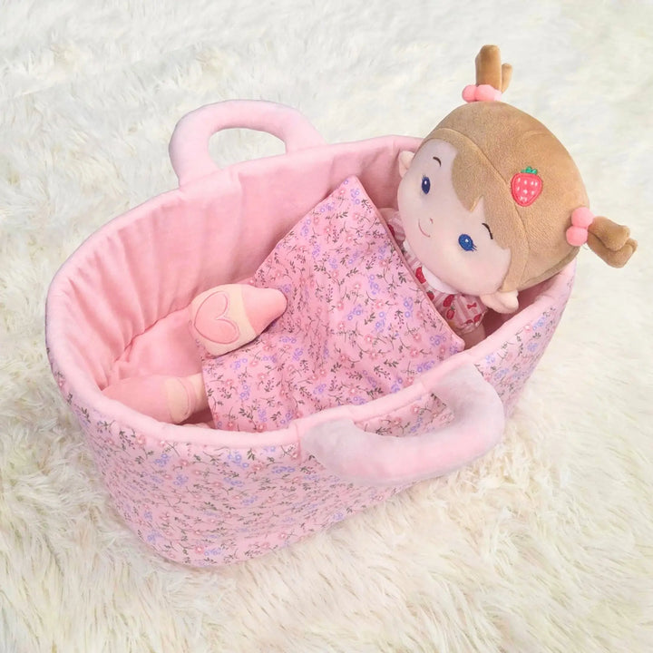 Strawberry Girl plush doll lying in 13-inch Caregiver Playset bassinet with matching blanket for pretend doll care