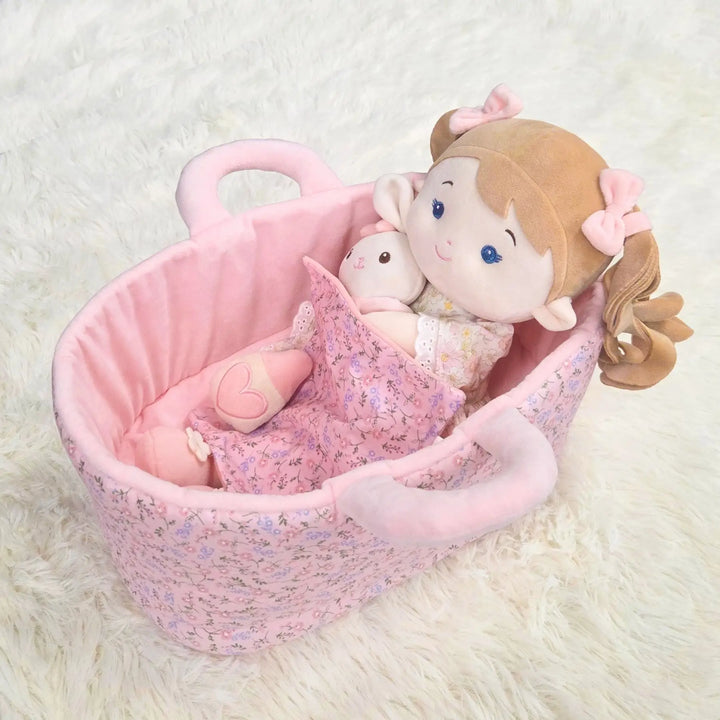 Mabel & Her Lovey plush doll lying in 13-inch Caregiver Playset bassinet with matching blanket for pretend doll care