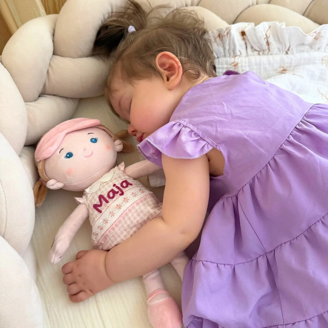 Baby cuddling Sophie soft talking doll at bedtime