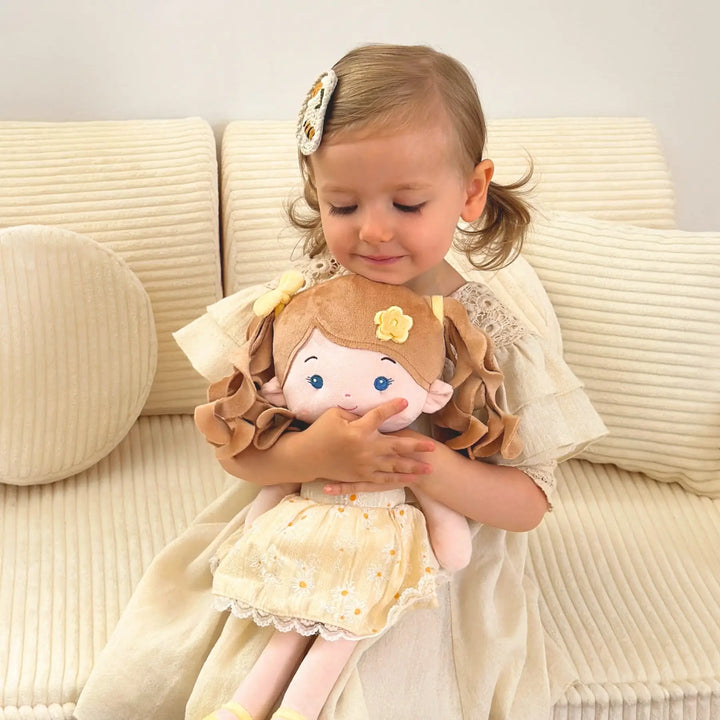 Baby girl hugging Daisy Girl plush doll during playtime on a sofa